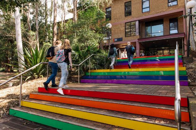 Four students on the UOW Wollongong campus walking up the rainbow coloured steps