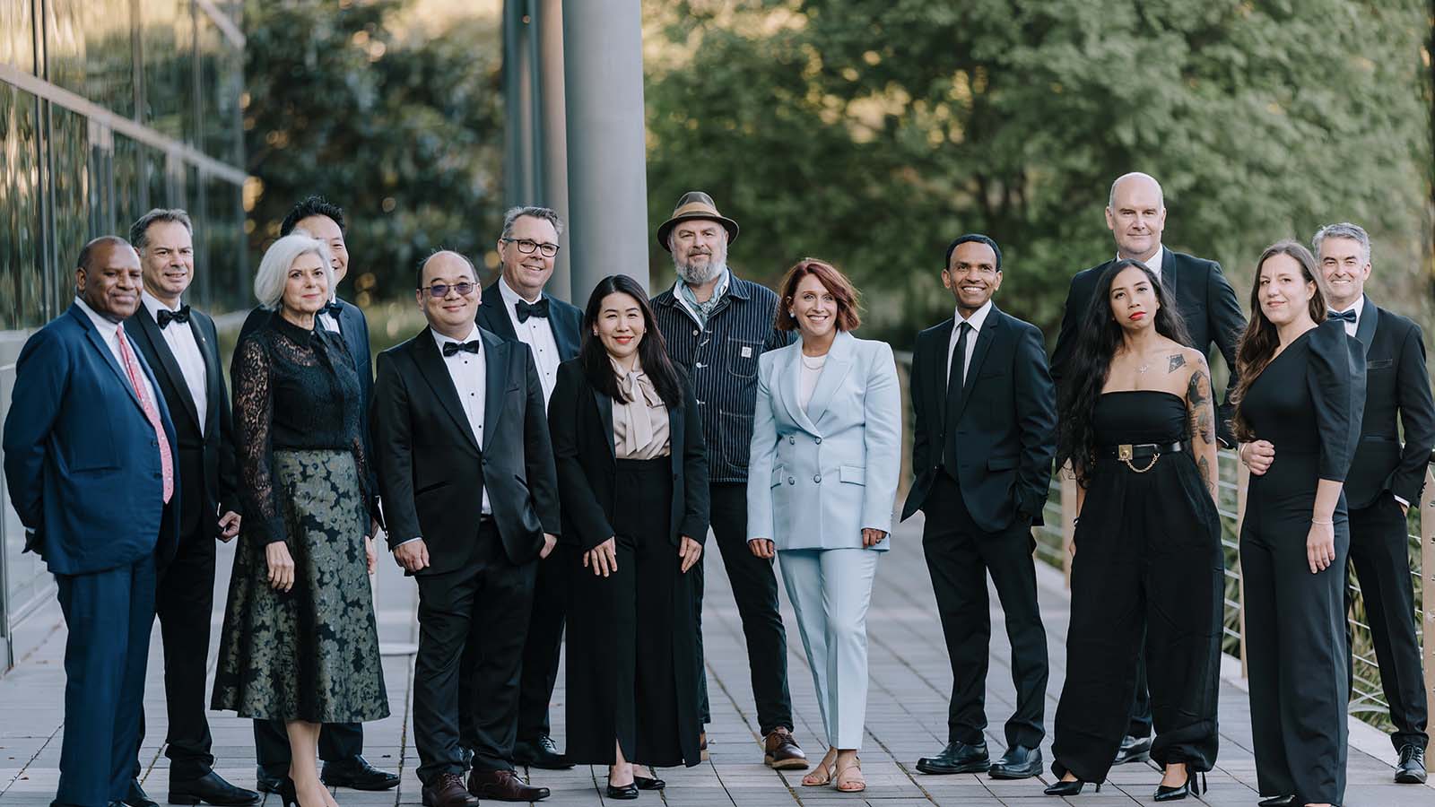 A group of people in black tie attire standing outdoors in front of a building