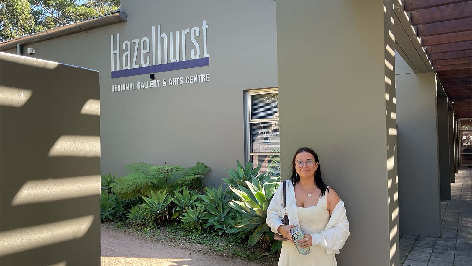 A woman is standing out the front of the Hazelhurst Regional Gallery and Arts Centre