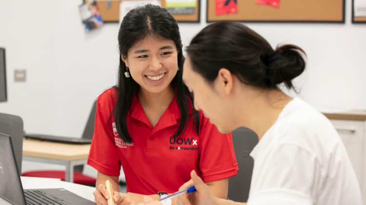 UOWx student in red shirt smiles at another student in white shirt
