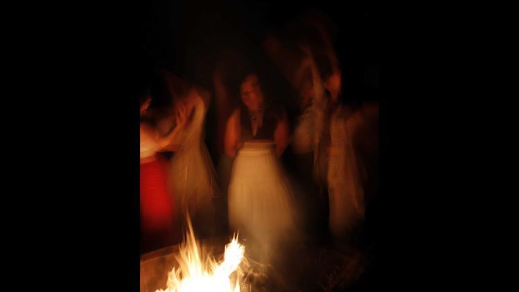 Blurry representation of a woman and others standing around a fire