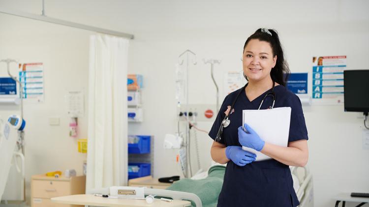 UOW Nursing student, Kayla Croffs in a hospital room holding a clipboard