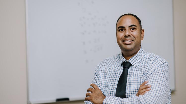 UOW Master of Education student, Dinesh Dodhy wears a checked shirt and a black tie.