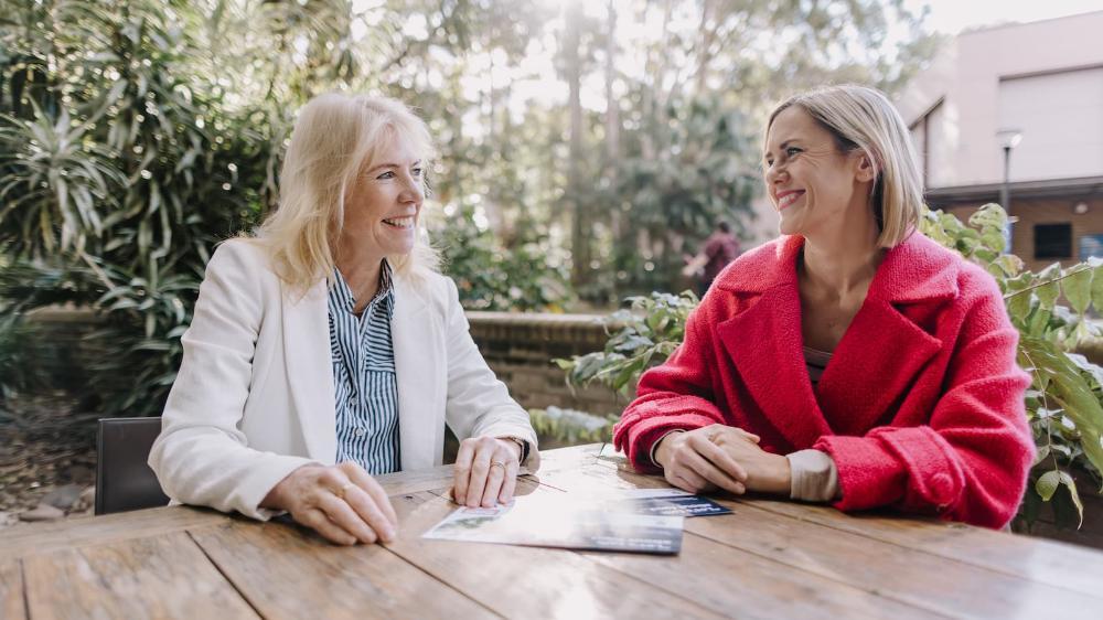 Karen Charlton and Katherine Kent chat to each other at a table outdoors. Photo: Michael Gray