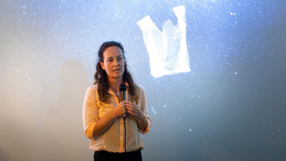 Karen Raubenheimer speaks to a group with a picture of a plastic bag in the ocean in the background. Photo: Paul Jones