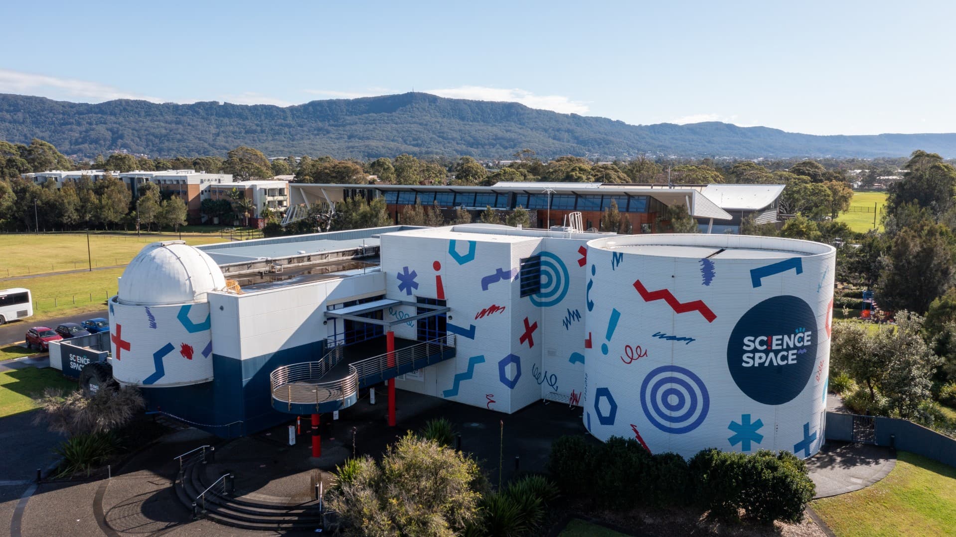 The Science Space building, on Innovation Campus, is pictured from the air. It is painted white and covered in blue, purple and red symbols. Photo: Tourism Australia
