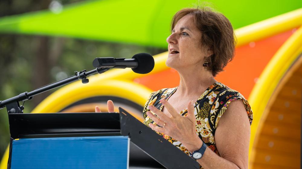 A woman stands at a lectern to deliver a speech to open a playground. Photo: Paul Jones