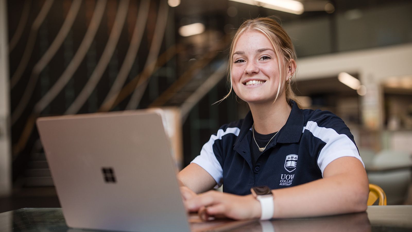 High school student Elouise Hicks is jump starting her career in the fitness industry by completing a School-Based Apprenticeship and Traineeship (SBAT) program through UOW College Australia. Photo of Elouise smiling at the camera in front of her laptop. Photo: Michael Gray.