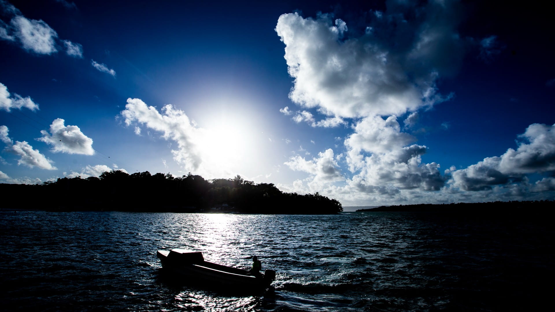 A fishing boat surrounded by water with a Pacific island in the background. Photo: Paul Jones